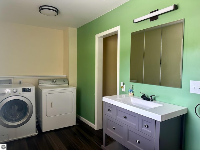 washroom with sink, washer and dryer, and dark hardwood / wood-style floors