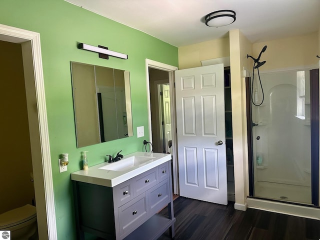 bathroom with hardwood / wood-style floors, vanity, toilet, and walk in shower