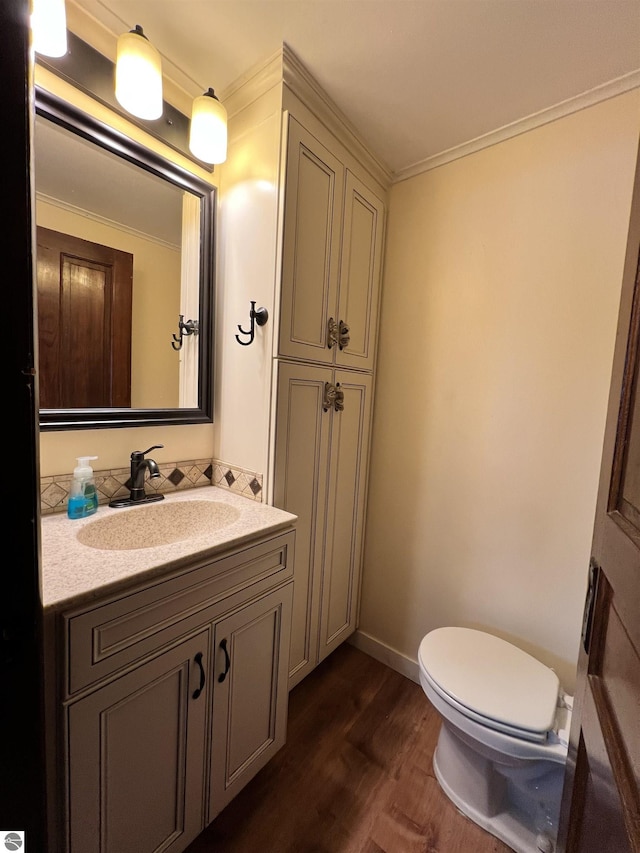 bathroom with crown molding, vanity, wood-type flooring, and toilet