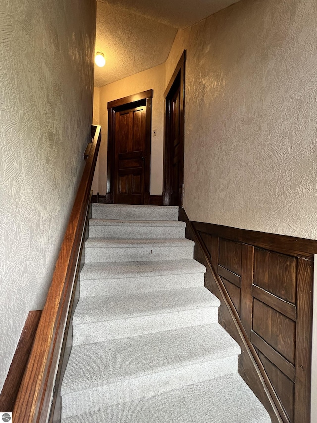 stairs featuring a textured ceiling