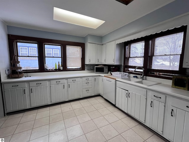 kitchen with dishwasher, white cabinetry, sink, and light tile patterned floors