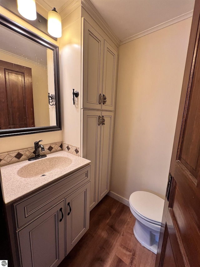 bathroom featuring hardwood / wood-style floors, vanity, toilet, and crown molding