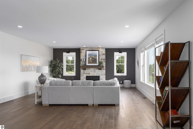 living room featuring dark wood-type flooring and a stone fireplace