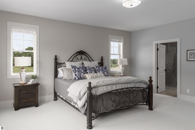 bedroom with ensuite bath, carpet floors, and multiple windows