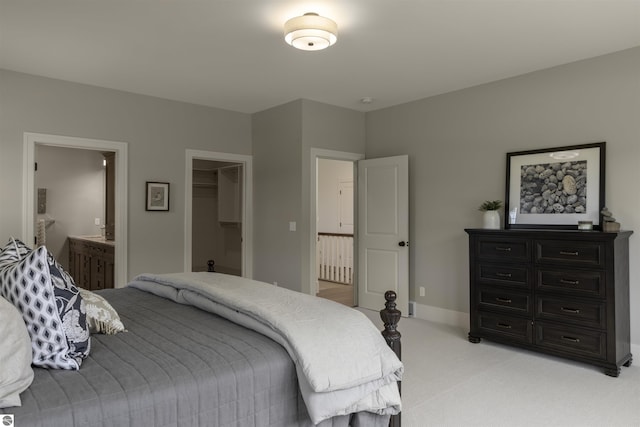 carpeted bedroom featuring ensuite bath, a closet, and a walk in closet