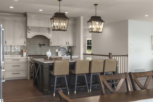 kitchen featuring decorative light fixtures, a breakfast bar area, high end stove, and a kitchen island