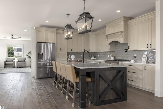 kitchen with a center island with sink, ceiling fan, stainless steel appliances, hanging light fixtures, and a breakfast bar