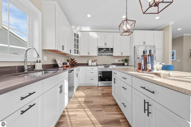 kitchen with white cabinetry, stainless steel appliances, a notable chandelier, pendant lighting, and sink