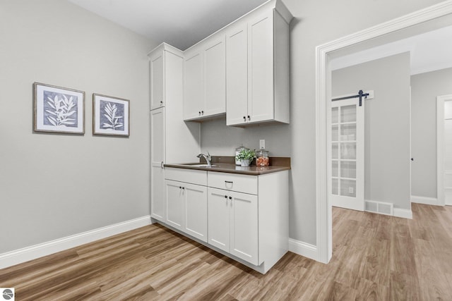 interior space featuring light hardwood / wood-style flooring, a barn door, and white cabinets