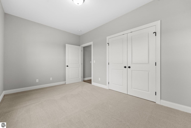 unfurnished bedroom with light carpet and a closet