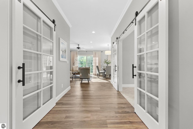 hallway featuring light wood-type flooring, crown molding, and french doors