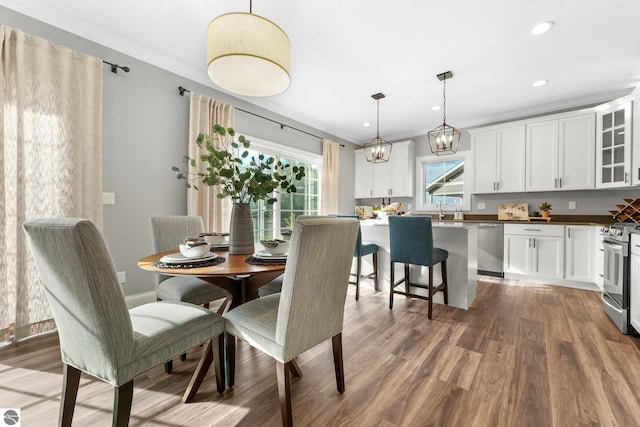 dining area featuring crown molding, hardwood / wood-style floors, and sink