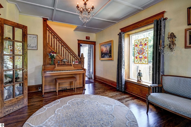 sitting room featuring dark hardwood / wood-style floors, an inviting chandelier, and coffered ceiling