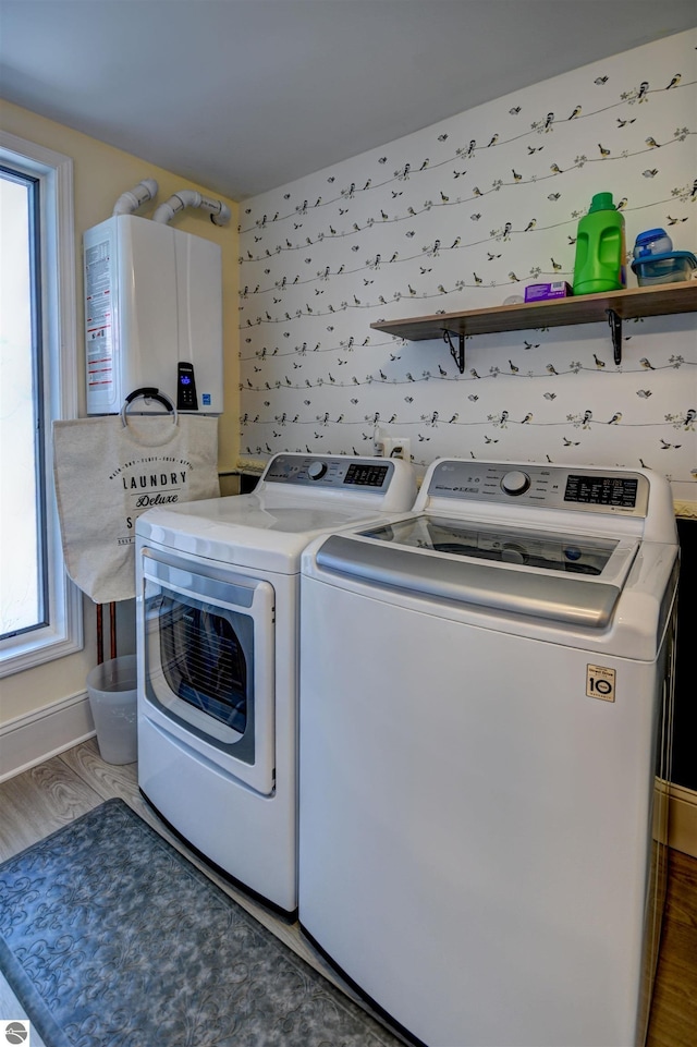 laundry area featuring a wealth of natural light, hardwood / wood-style flooring, water heater, and independent washer and dryer