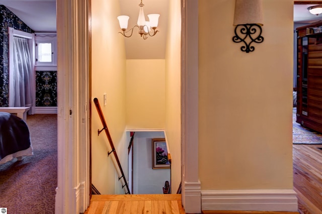 stairs with carpet and an inviting chandelier