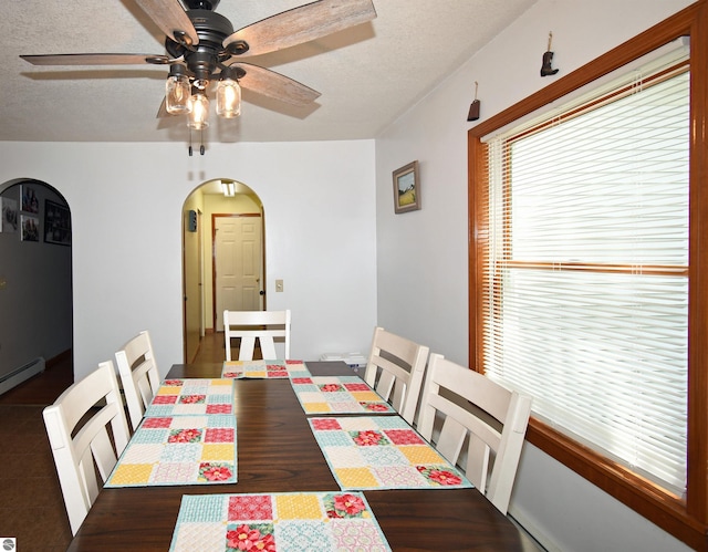 dining space with ceiling fan, a textured ceiling, and a baseboard heating unit