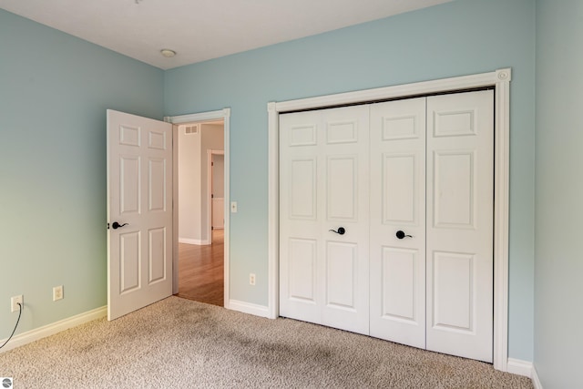 unfurnished bedroom featuring carpet flooring, baseboards, visible vents, and a closet