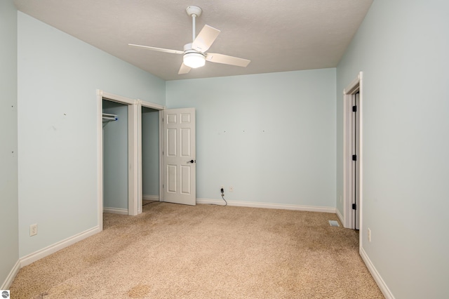 unfurnished bedroom featuring a ceiling fan, baseboards, light carpet, and a closet