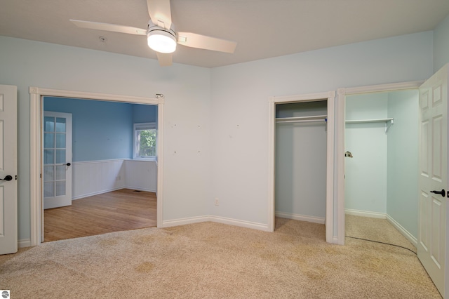unfurnished bedroom with ceiling fan, light carpet, and two closets