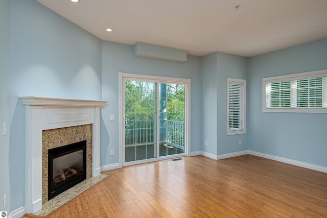 unfurnished living room featuring visible vents, a high end fireplace, wood finished floors, baseboards, and recessed lighting