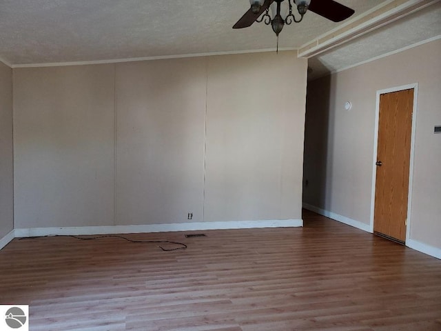 empty room with light wood-type flooring, a textured ceiling, ceiling fan, crown molding, and vaulted ceiling with beams