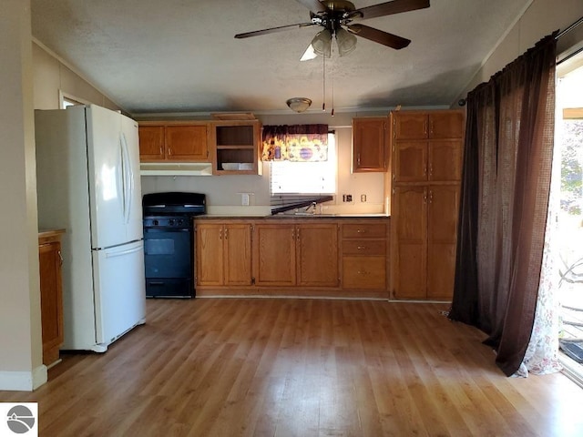 kitchen with gas stove, ceiling fan, sink, white refrigerator, and light hardwood / wood-style floors