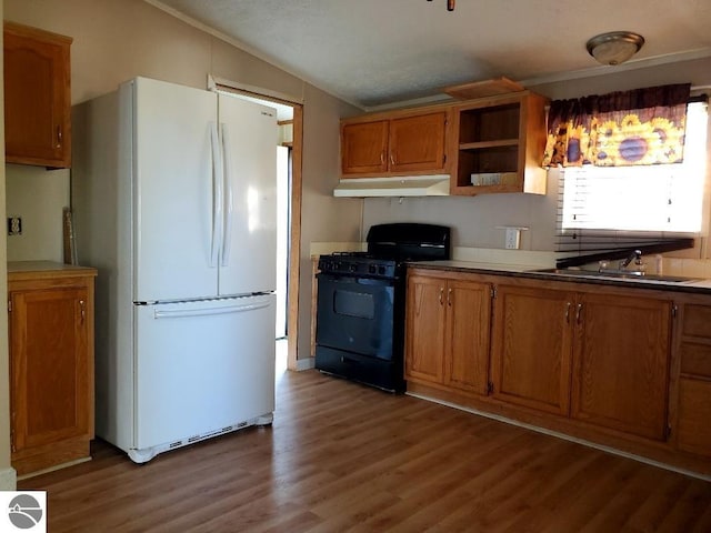 kitchen with lofted ceiling, white refrigerator, sink, wood-type flooring, and black range with gas cooktop