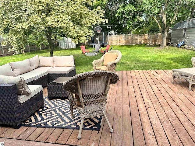 deck with an outdoor living space, a trampoline, and a yard