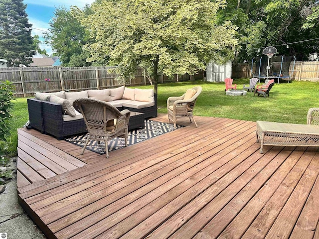 deck with a lawn, outdoor lounge area, a storage unit, and a trampoline