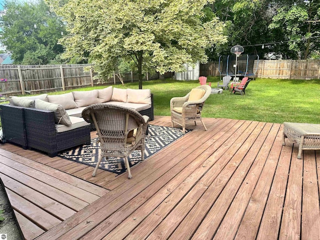 wooden deck featuring a yard, an outdoor living space, and a trampoline