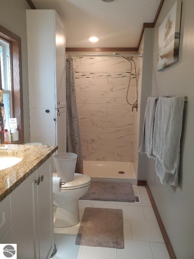 bathroom featuring tile patterned flooring, vanity, toilet, and walk in shower