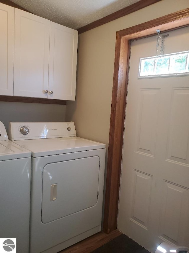 laundry area featuring cabinets, a textured ceiling, and washing machine and clothes dryer