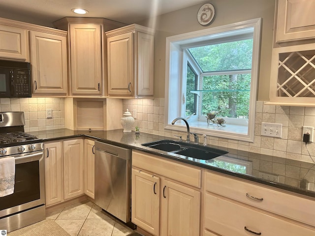 kitchen featuring dark stone counters, sink, light tile patterned floors, tasteful backsplash, and stainless steel appliances