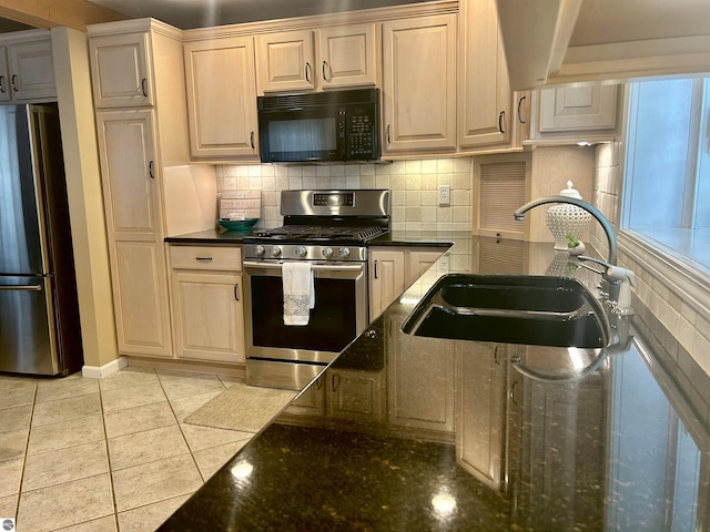 kitchen featuring light tile patterned flooring, stainless steel appliances, dark stone counters, and sink