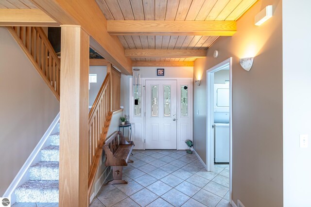 tiled foyer entrance with beam ceiling, wooden ceiling, and stacked washer / drying machine