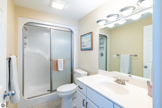 bathroom with tile patterned floors, vanity, toilet, and a shower with shower door