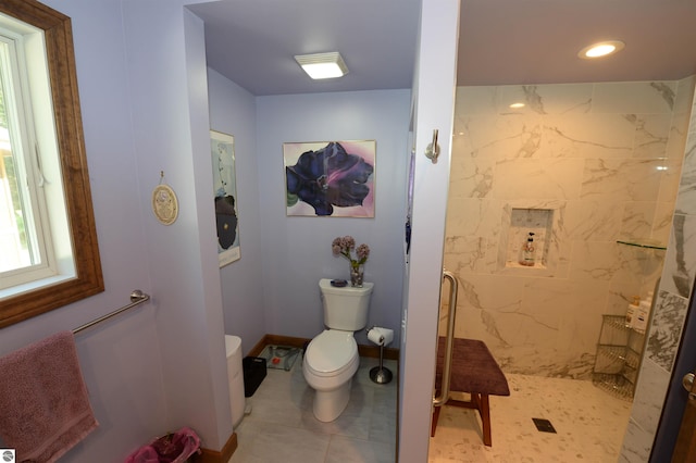 bathroom featuring tiled shower, toilet, and tile patterned floors