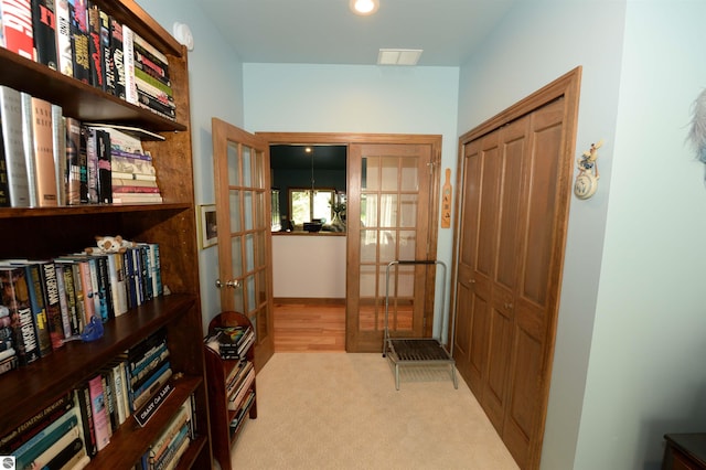 hall with french doors and light colored carpet