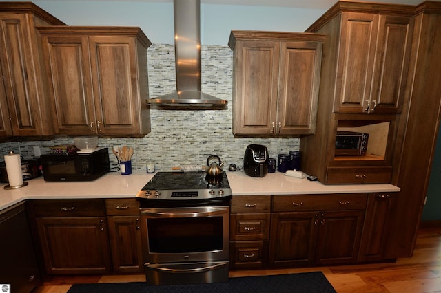 kitchen featuring decorative backsplash, black appliances, light hardwood / wood-style flooring, and wall chimney range hood