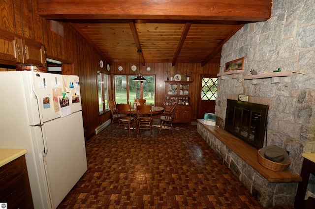 kitchen featuring white fridge, a fireplace, vaulted ceiling with beams, wooden walls, and wood ceiling