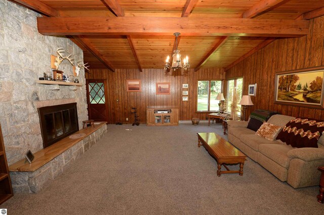 living room with wood ceiling, a stone fireplace, wooden walls, and carpet flooring