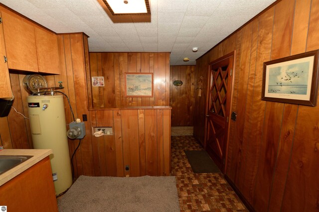 interior space with wood walls, water heater, and dark tile patterned flooring