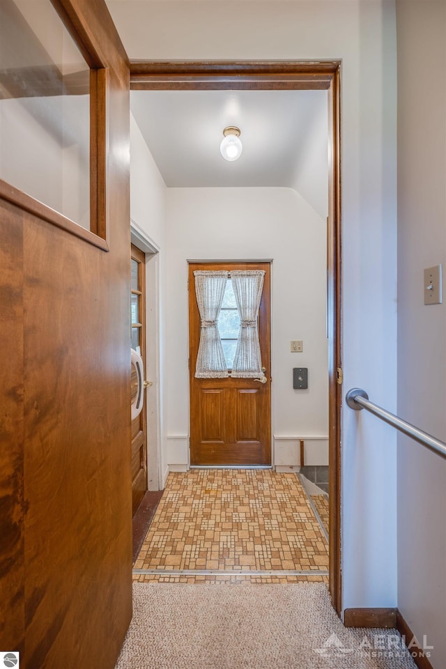 entryway with carpet and vaulted ceiling