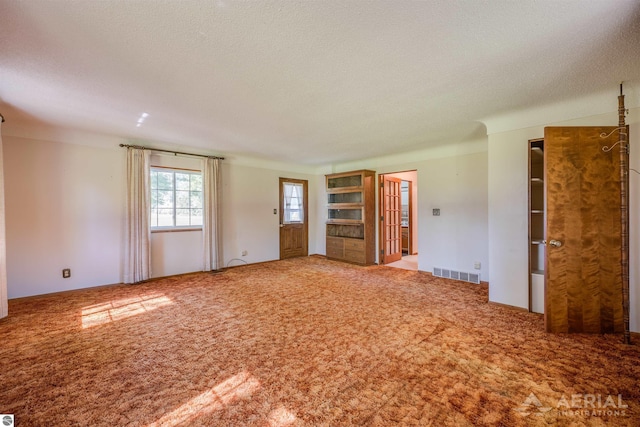 carpeted empty room featuring a textured ceiling