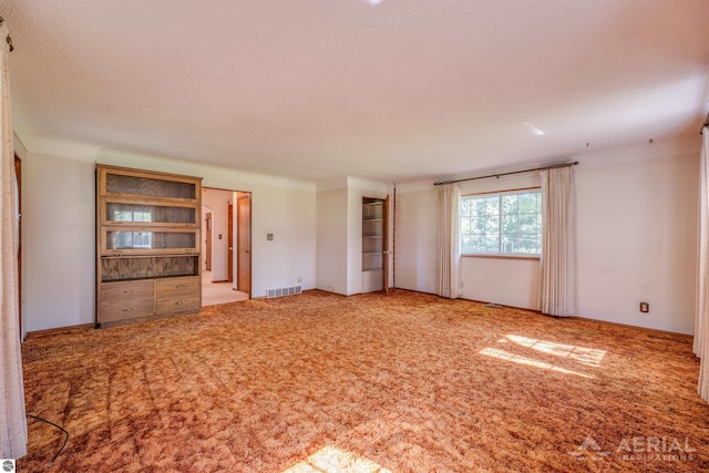 empty room with light colored carpet and a textured ceiling