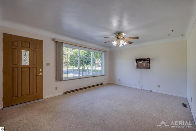 empty room with light colored carpet, a baseboard radiator, a wall mounted AC, and ceiling fan