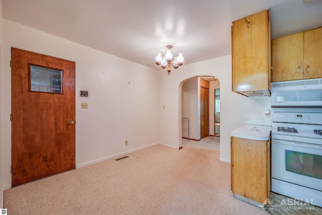 kitchen featuring light carpet, white appliances, and a notable chandelier