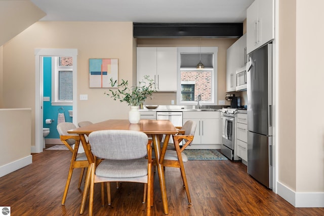 dining area with dark hardwood / wood-style floors, beamed ceiling, and sink