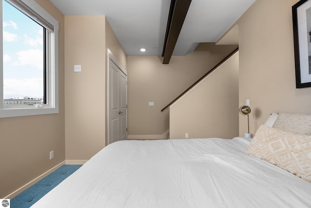 carpeted bedroom with beam ceiling and multiple windows