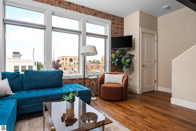 living room with brick wall and dark wood-type flooring